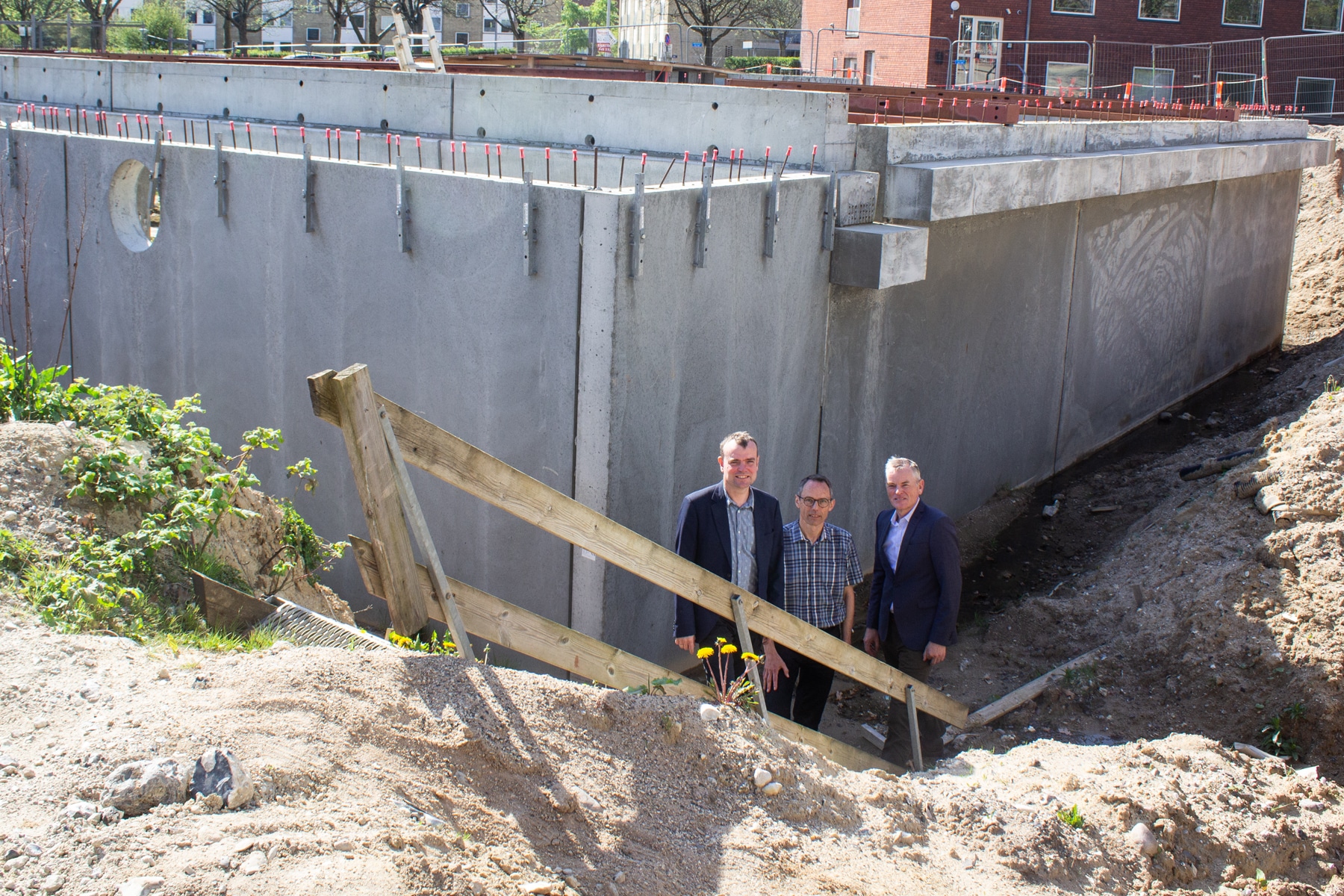 Grå betonmure markerer lige nu grundplan for bygningen bag Menighedsfakultetet. På billedet ses fakultetsleder Thomas Bjerg Mikkelsen, sekretariatsleder Walther Hansen og fondsformand Peter N. Andersen.